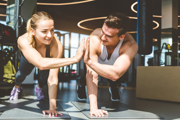 Couple Woman and man in the gym is warming up before training, stands in plank