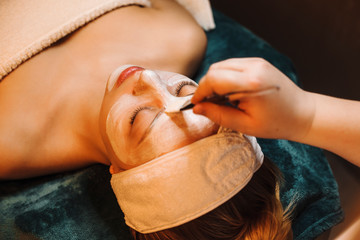Upper view close up of a cheerful woman leaning on a bed with closed eyes having a white anti acne...