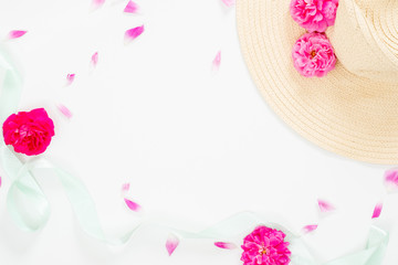 Minimal style composition with beach straw hat, pink rose flowers bud and petal and blue mint ribbon on white background. Flat lay, top view still life concept.