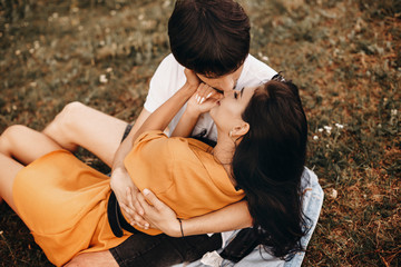Upper view of a beautiful caucasian couple embracing and looking at each other before kissing while sitting on the ground on a field.