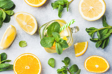 Lemonade drink of soda water, lemon and mint leaves in jar on light background.