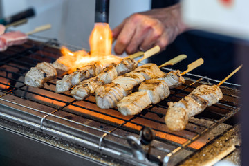 A Man Is Cooking Fresh Tuna Sticks On A Grill.