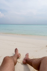 Relax on the beach. In the frame of the guy's feet.