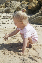 : Little toddler girl playing with sand at the beach