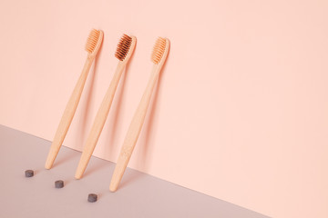 Bamboo toothbrush and dry tooth paste or toothpaste tablets on pink blue background. Zero waste, ecological concept.