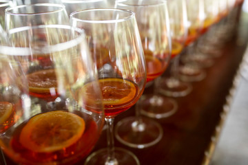 A lot of cocktails at the bar at the wedding party. Glasses with apperol and with a slice of lemon close-up