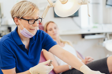 Zahnärztin bereitet den Bohrer vor während einer Behandlung - obrazy, fototapety, plakaty