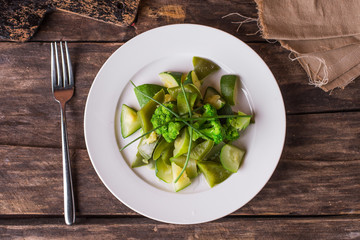 Boiled green vegetables broccoli, pepper and zucchini on a white plate