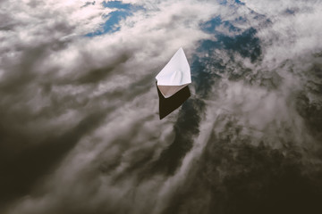 white paper boat on a pond. Ship is floating in the water with reflected sky