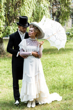 Handsome Victorian Man Standing With Attractive Woman Holding Umbrella