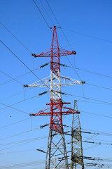 Metallic pylons of high-voltage power lines against a blue sky. The concept of power, transportation of electrical energy. Bottom view. Selective focus.