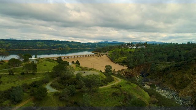 Aerial View  Dam Village waterfront  4K Helicopter Shot  landmark trees road cars cloudes california lake
