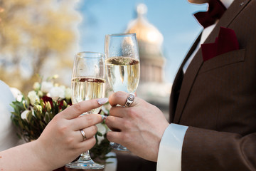 Close up of new married couple toasting champagne glasses at wedding party. Bride and groom hands clinking glasses at wedding reception.