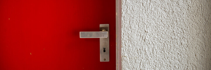 closed metal door with a handle and plastered wall.