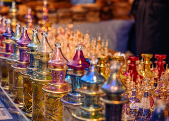 Close together standing richly decorated and colored perfume flacons made of glass in the light of...