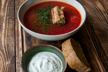 Borscht with sour cream on a wooden table.