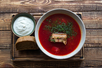 Borscht with sour cream on a wooden table.