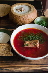 Borscht with sour cream on a wooden table.