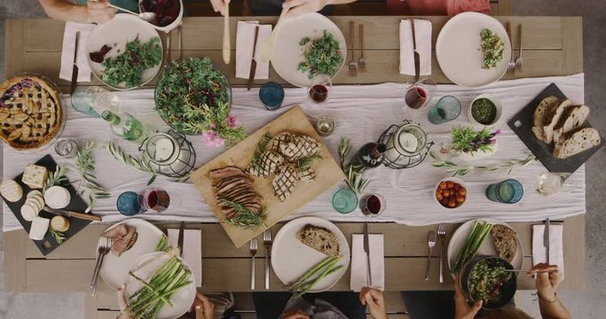 Friends Having A Dinner Party Together, Top Down View Of Dinner Table With Six Friends Serving Food And Making Dinner Plates