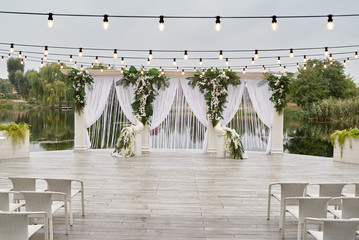 Place for wedding ceremony with wedding arch decorated with palm leaves, orchid flowers and floral...