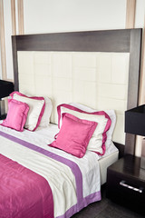 Hotel bedroom interior with double bed and bedside table, copy space. Large buttoned headboard of luxury bed, copy space. Checkered soft headboard