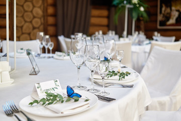 Table setting with blank guest card on empty white plate and cutlery on table, copy space. Menu mockup, place setting at wedding reception. Table served for wedding banquet in restauran
