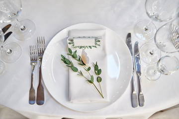 Table setting with blank guest card on empty white plate and cutlery on table, copy space. Menu...