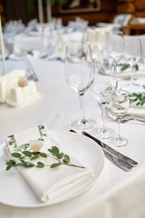 Table setting with blank guest card on empty white plate and cutlery on table, copy space. Menu mockup, place setting at wedding reception. Table served for wedding banquet in restauran