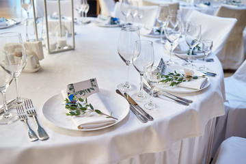 Table setting with blank guest card on empty white plate and cutlery on table, copy space. Menu mockup, place setting at wedding reception. Table served for wedding banquet in restauran