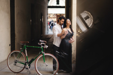 Fototapeta na wymiar Photo session of love couple. A man and a woman are walking in the old city with a green retro bike