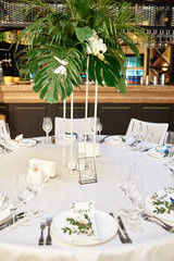 Table setting with cutlery, wineglasses and flower decorations on table, copy space. Place setting at wedding reception. Table served for wedding banquet in restauran