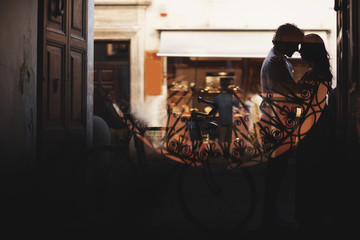 Silhouette of a love couple. Man and woman gently hug. Walk with a bike