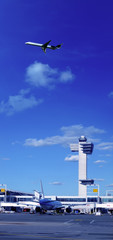 Transportation image of flying commercial passenger airplane over airport and sunny blue sky