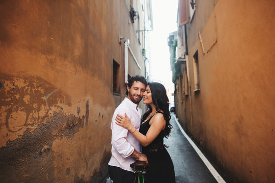 Loving couple gently leaning against each other in the old city. Behind them is the background of a terracotta wall