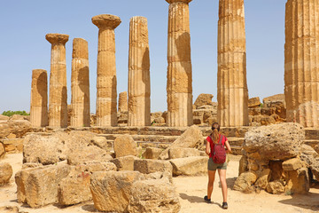 Young woman walking in the Valley of the Temples Agrigento, Sicily. Traveler girl visits Greek Temples in Southern Italy.