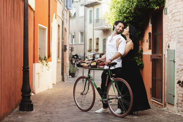 Fototapeta premium Walking a couple of lovers in the streets of the old city, with a bicycle. The woman gently hugs her man