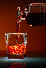 Alcoholic drink pouring from a decanter into a glass.