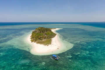 Tropical island Canimeran with sandy beach in the blue sea with coral reef, top view. Balabac, Palawan, Philippines. Small island with palm trees and white sand.