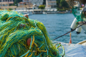 Yellow and green fishing net on the dock in harbor by the sea in summer day close up