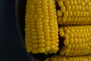 Fresh cooked yellow corn cobs lie on a gray dish