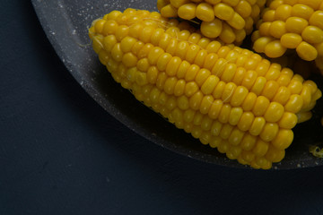 Fresh cooked yellow corn cobs lie on a gray dish