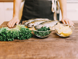 Unrecognizable woman cooking fish in the kitchen.