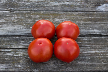 Four ripe red tomatoes on an old wooden table