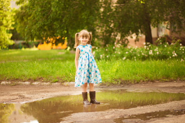 Naklejka premium Little kid girl runs through a puddle. summer outdoor