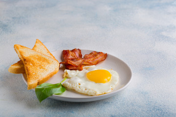 Fried egg with bacon and toast decorated with basil leaves on a white background. English breakfast. with space for your text