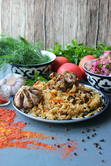 Pilaf on a platter of meat and spices.pilaf in a plate on a wooden background, top view.  The concept of Oriental cuisine. Homemade Uzbek pilaf of lamb is served in cast iron cookware. Copy space.