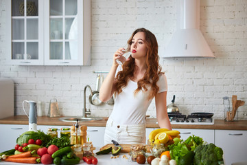 Young woman drinking fresh water from glass in the kitchen. Healthy Lifestyle and Eating. Health, Beauty, Diet Concept.