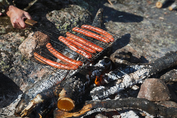 man fries sausages on the fire