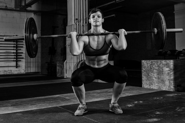 Junge kurzhaarige Frau mit Muskeln beim Workout mit der Langhantel. Die hübsche athletische...