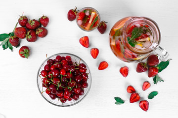 View from above of red berries and fruits. Health nutrition. Strawberry mojito with sweet cherry and strawberry on a white wooden background